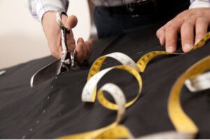 A man cutting suit fabric for a custom fit.